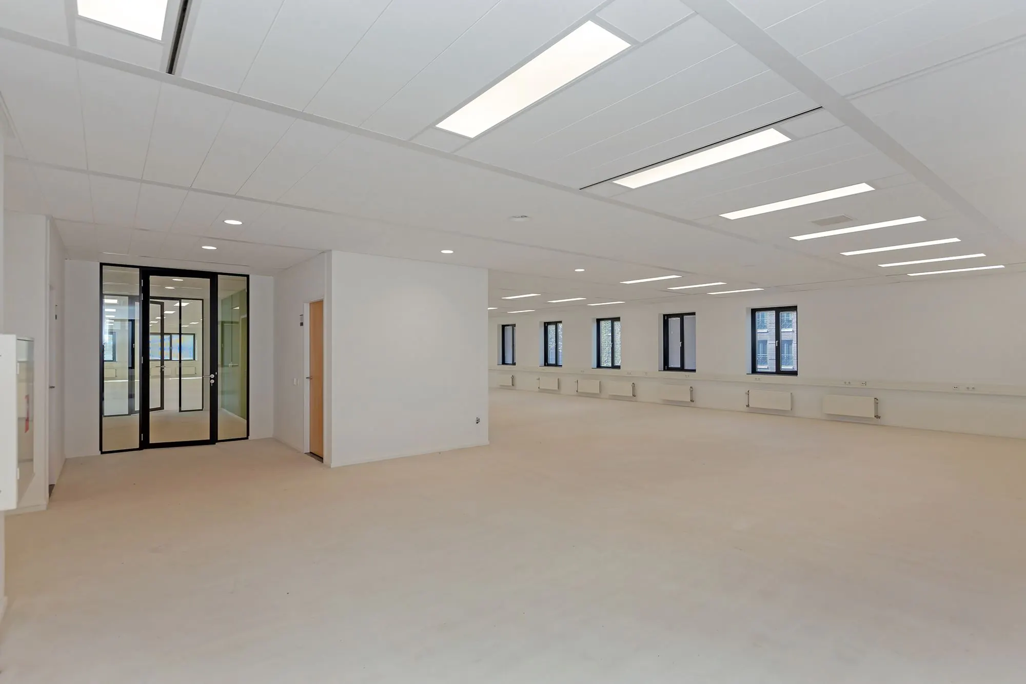 Lichte, lege kantoorruimte aan de Boris Pasternaklaan met wit plafond, ingebouwde verlichting en zwarte kozijnen.